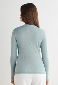 Jasnoniebieski longsleeve w prążkowanej teksturze, z okrągłym dekoltem i dopasowanym krojem, o gładkim wykończeniu i minimalnych detalach.