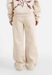 Beige oversized sweatpants met een zachte textuur, wijd gesneden ontwerp en elastische tailleband. Geschikt voor casual draag en comfort.