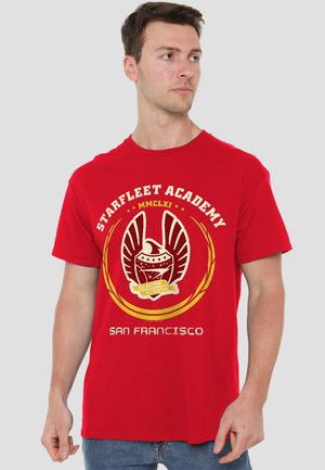 Rotes Baumwoll-T-Shirt mit einem auffälligen Grafik des Starfleet Academy-Emblems in Gold, mit dem Text "SAN FRANCISCO" am unteren Rand.
