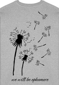Tela gris con un gráfico de diente de león negro y semillas dispersándose. El texto debajo dice: "seremos efímeros."