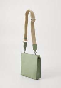 Green leather crossbody bag with a textured surface. Features a beige fabric strap and metal hardware. Simple, rectangular shape.