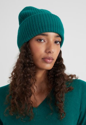 Teal ribbel gebreide beanie met een slouchy pasvorm, voorzien van een textuurpatroon. De stof lijkt zacht en warm, geschikt voor koud weer.
