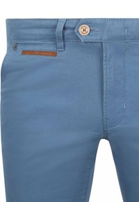 Helle blaue Hose aus glattem Stoff, mit einem braunen Lederakzent an der Tasche, Knopfverschluss und Gürtelschlaufen.