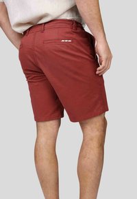 Shorts pour hommes couleur bordeaux en coton, avec une poche arrière au design décoratif, coupe ajustée et texture lisse.
