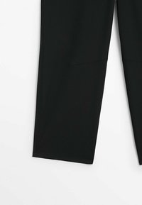 Pantalon noir à jambes droites avec détail de couture visible au niveau des genoux, montré de mi-cuisse à la cheville sur un fond blanc.