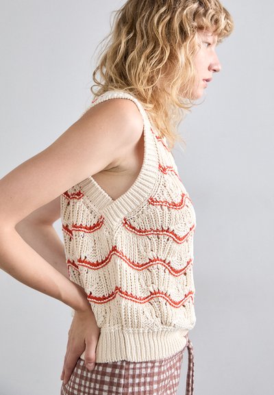 Haut sans manches en crème avec des motifs ondulés rouges, des détails texturés et un ourlet côtelé. Doté d'un col en V et de côtés ouverts.