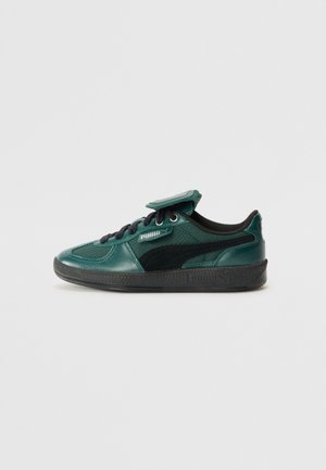 Zapatilla deportiva verde de ante y sintética con detalles en negro, punta redonda, diseño con cordones y lengüeta acolchada con parche de logo. Suela de goma.