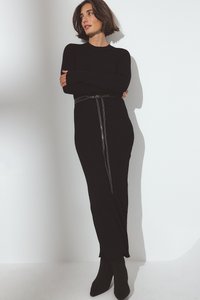 Črna rebrasta pletena obleka z dolgimi rokavi, ki vsebuje srebrno zadrgo in črni pas. V kombinaciji s črnimi čevlji z izostrenim prstom do gležnjev.