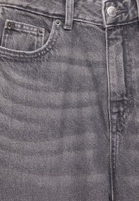 Mörkgrå denimjeans med en klassisk femficksdesign, synliga sömmar och en kontrasterande knapp med varumärkeslogotyp.