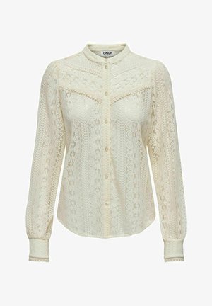 Pusero pitsistä off-white-värissä, jossa on monimutkaiset kuviot, pitkät hihat, nappikiinnitys edessä ja mandariinikaulus. Hienovarainen pitsi hihansuissa.