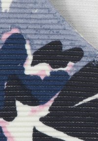 Tissu texturé avec des motifs floraux bleu foncé et marine sur un fond clair, avec de fines lignes horizontales créant un effet strié.