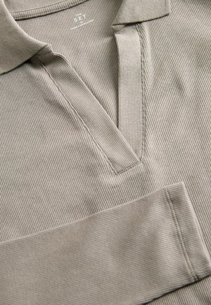 Beżowa koszulka polo z prążkowanym wzorem, o dekolcie w kształcie litery V, z teksturowanym materiałem i widocznymi detalami st�ębnowania na plisie i rękawach.