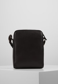Borsa a tracolla nera in pelle con forma rettangolare, superficie texturizzata, chiusura con zip e tracolla regolabile. Design minimalista, senza branding visibile.