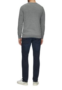 Szary sweter dzianinowy z okrągłym dekoltem, noszony z ciemnoniebieskimi dżinsami i białymi trampkami, widok od tyłu. Casualowy design, ściągacze przy mankietach.