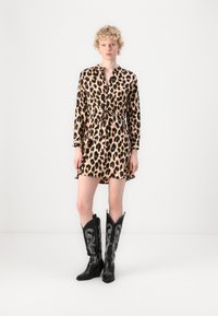 Leoparda raksts kleita ar garām piedurknēm, auduma josta un pogu priekšpuse. Saskaņota ar garām melnām kazaku zābakiem ar izšuvuma detaļām.