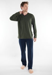Green long-sleeve V-neck shirt with white vertical stripes, paired with navy blue loose-fitting pants. Soft fabric, relaxed silhouette.
