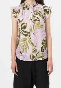 Top à imprimé floral, tissu léger, principalement rose clair avec des accents verts, manches à volants, col ouvert avec détail en bouton.