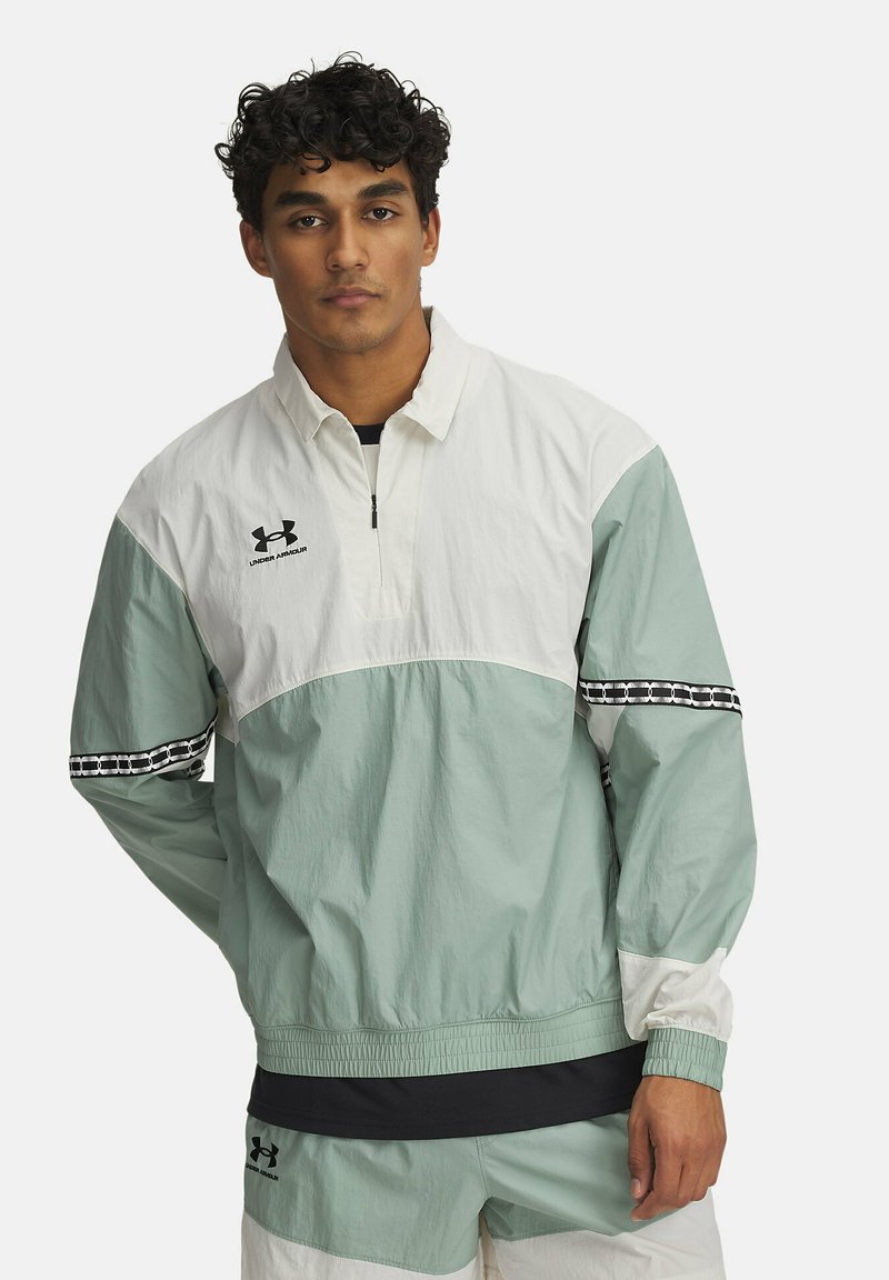 Chaqueta ligera estilo rompevientos en verde menta y blanco, con cierre de media cremallera, puños elásticos y acentos a cuadros en las mangas.