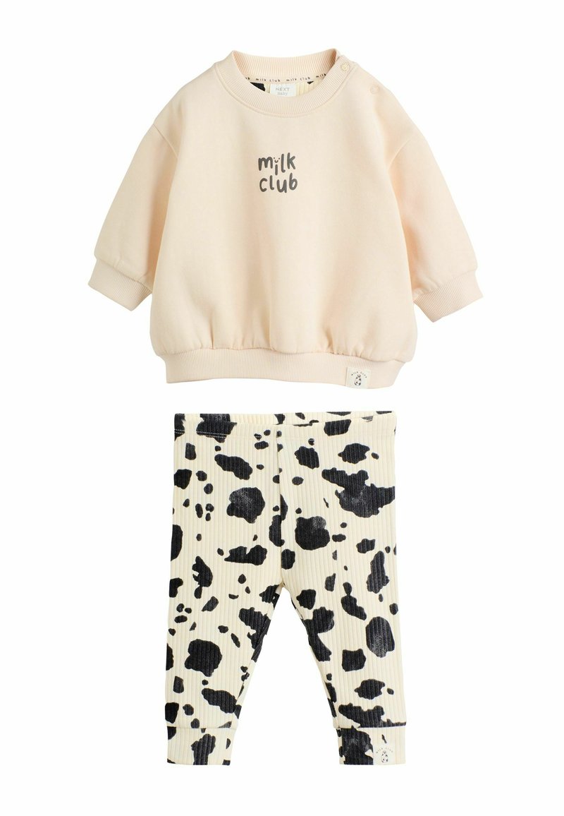 Sudadera de color rosa claro con gráfico de "milk club" y puños acanalados, combinada con leggins acanalados color crema que presentan un patrón de manchas de vaca negras.