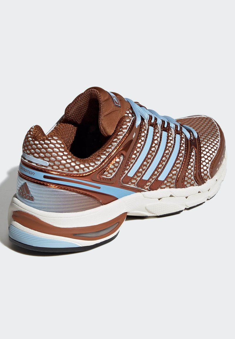 Chaussure de course marron avec tige en maille, accents bleus, surface texturée et semelle coussinée. Présente trois bandes blanches et des détails de marque.