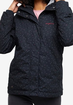 Mujer con chaqueta acolchada negra con pequeños patrones de corazones y un logo rosa en el pecho, ajustándose el cuello de la capucha.