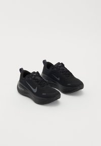 Paire de chaussures de course Nike ZoomX noires avec un design à lacets et semelles épaisses et coussinées sur fond blanc.
