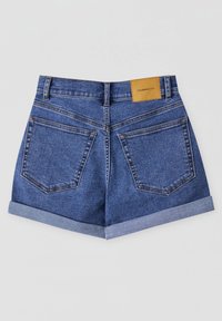 Shorts en denim bleu avec revers roulés, deux poches arrière, passants pour ceinture et un écusson de marque en cuir beige sur la ceinture.