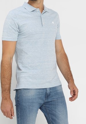 Světle modré polo tričko s krátkým rukávem a texturovaným povrchem. Obsahuje límec a malé vyšívané logo na hrudi. V kombinaci s modrými džíny.