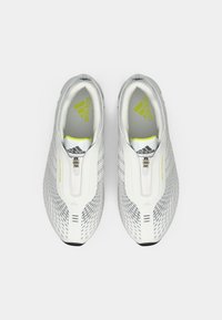 Biele športové topánky s hornou časťou z oka, so zipsovým zapínaním, čiernou podrážkou a jemnými žltými akcentmi. Textúrovaný vzor na stranách.