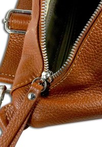 Sac en cuir marron avec une surface texturée, fermeture éclair en métal et sangle. La doublure intérieure semble être d'une couleur unie. Possède des accents en métal.