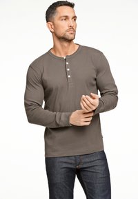 Donkergrijze langslavige henley-shirt van zachte stof, met een drieknoopsluiting en fitted mouwen, gecombineerd met donkere spijkerbroek.