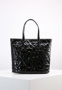 Czarna torebka z lakierowanej skóry z podwójnymi uchwytami, z błyszczącą powierzchnią i wypukłym wzorem serca. Ustrukturyzowany prostokątny kształt.