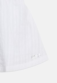 Λευκό υφασμάτινο με υφή, με διακριτικές κάθετες ρίγες και ασημί λογότυπο "BOSS" τυπωμένο κοντά στο κάτω μέρος.