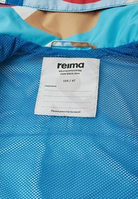 Blaue Netzinnenausstattung mit einem weißen Stoffetikett, auf dem "reima" steht, Größe 104/4T und Pflegeanweisungen; hat eine atmungsaktive Textur und Muster.
