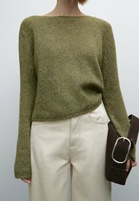 Olive green knitted sweater with a boat neckline, loose fit, and ribbed texture, paired with cream-colored wide-leg pants and a dark brown bag.