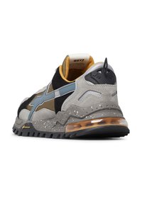 Sneaker sportive da uomo con suola grigia maculata, cuscino d'aria trasparente, tomaia beige e nera, fascia laterale blu e rivestimento interno giallo.