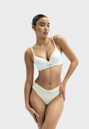 White padded bra with adjustable straps, paired with cream seamless underwear featuring logo waistband and minimal coverage design.