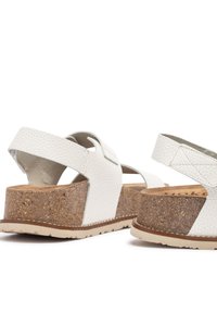Sandalias de plataforma blancas con textura y detalles de corcho, con correas ajustables. Presentan una suela sólida para tracción y un diseño de punta redondeada.