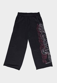 Juodos plačiomis kojomis kelnės iš minkštos medžiagos. Kairėje pusėje yra baltas ir raudonas genties raštas, elastinga juosmens juosta ir kišenės.