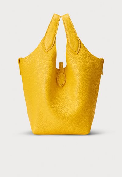Žuta kožna torba za nošenje na ramenu s teksturiranom površinom, karakterističnim dvostrukim ručkama i otvorenim vrhom. Glatki šavovi i detalji.