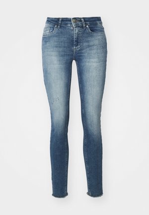 Jeans skinny blu in denim, con lavaggio sbiadito, leggero strappo sul davanti e orli sfrangiati alle caviglie.