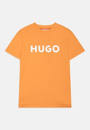 T-shirt orange à manches courtes et col rond avec un texte blanc "HUGO" centré sur le devant.