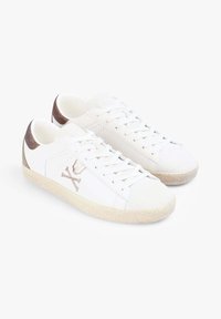 Scarpe da tennis bianche con una suola testurizzata di un bianco sporco, dettagli in un tan chiaro e un logo grafico sul lato. Presentano lacci piatti e una finitura in pelle liscia.