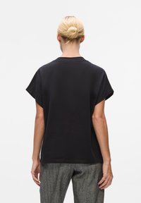 Schwarzes Übergrößenshirt mit Rundhalsausschnitt und kurzen Ärmeln. Hergestellt aus glattem Stoff, bietet einen lässigen Schnitt und einen sauberen Saum.
