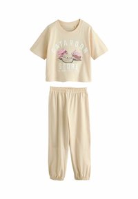 Completo pigiama in cotone beige chiaro composto da due pezzi. Maglietta a maniche corte con grafica "Cataroon Store" e pantaloni elasticizzati con polsini alle caviglie.