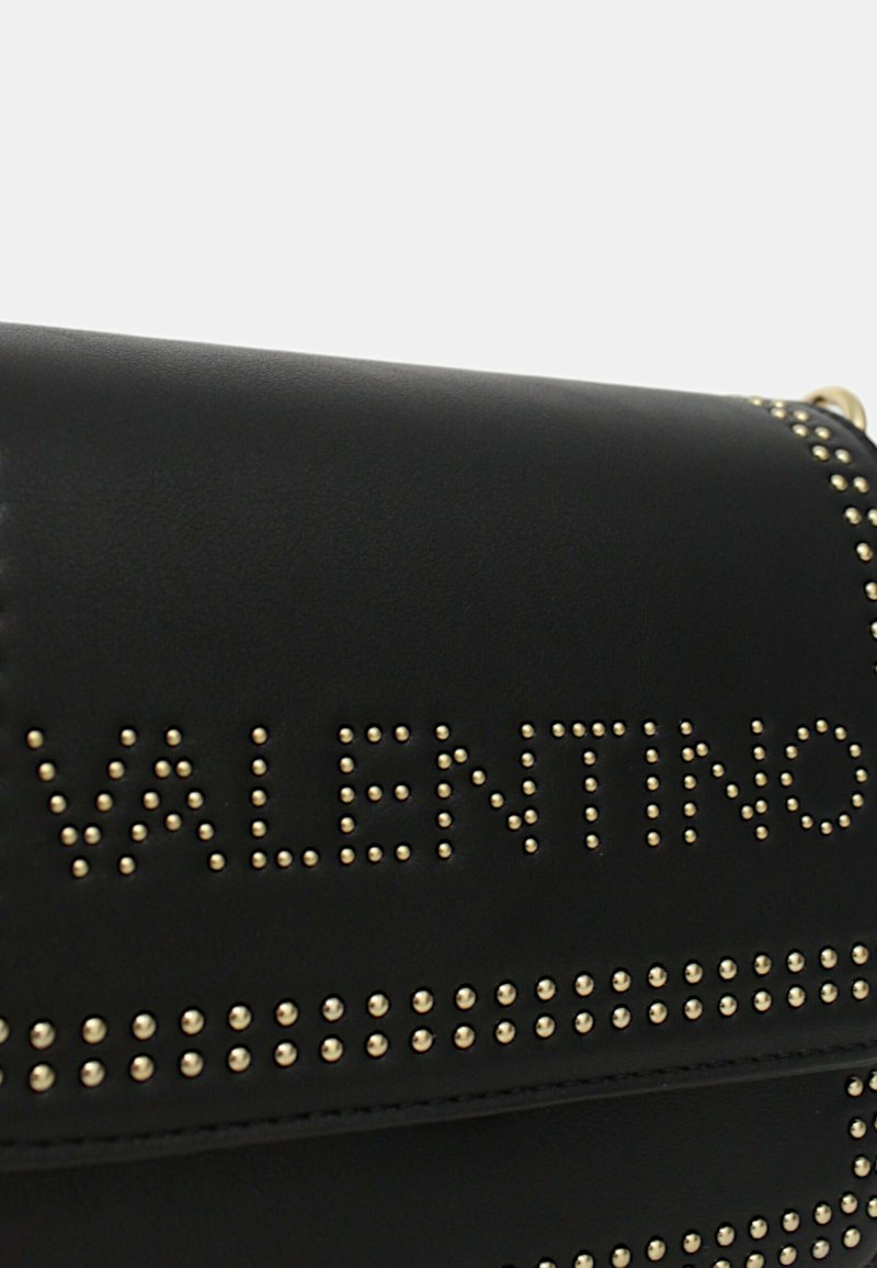 Bolso de cuero negro con acentos de tachuelas doradas. Presenta el texto "VALENTINO" en relieve y un diseño de solapa estructurada. Textura suave con detalles metálicos.