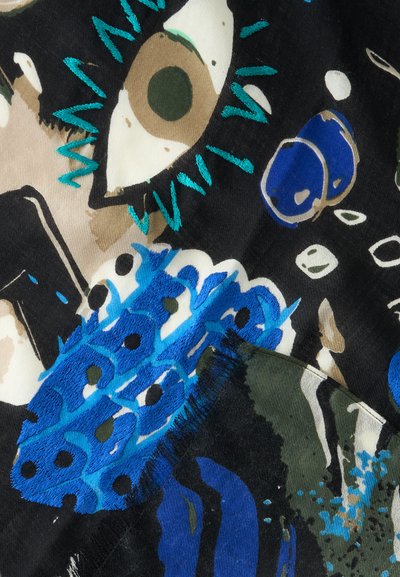 Design abstrait de tissu avec un grand œil marron brodé, des formes bleues et des pois noirs sur un fond noir avec des accents beige et verts.