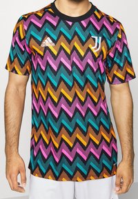 Grafisk kortärmad tröja med ett flerfärgat zigzagmönster i rosa, teal, orange och svart; tillverkad av andningsbart tyg.