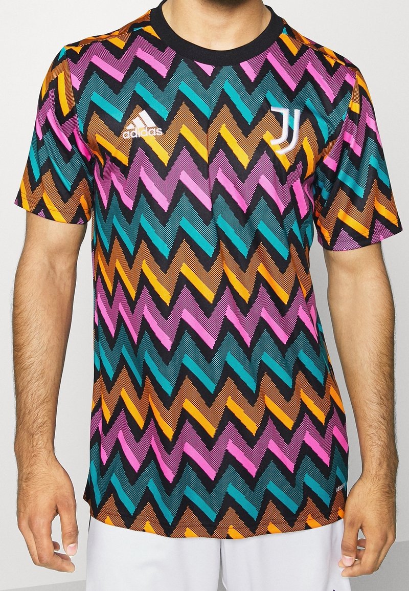 Grafisk kortärmad tröja med ett flerfärgat zigzagmönster i rosa, teal, orange och svart; tillverkad av andningsbart tyg.