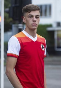 Rode voetbalshirt met oranje verloopmouwen, witte kraag en een logo op de linkerborst. Korte mouwen en een slim-fit design.